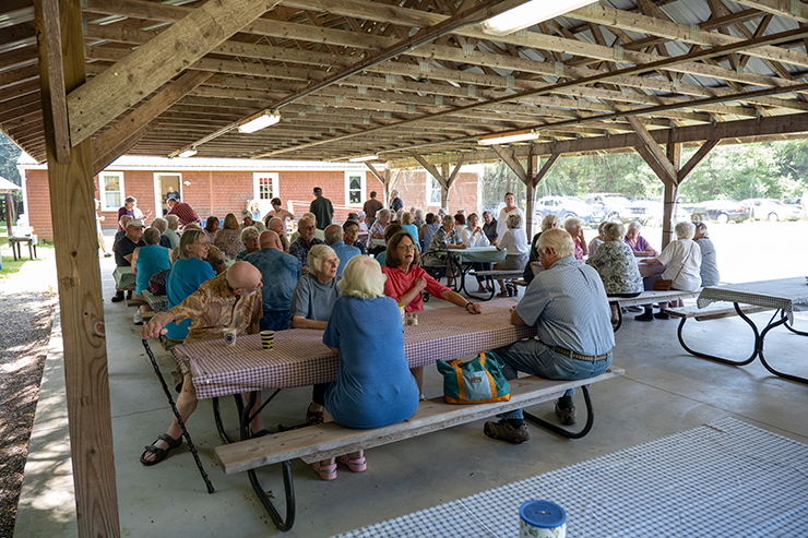 A group of people sitting at tables in a pavilion.